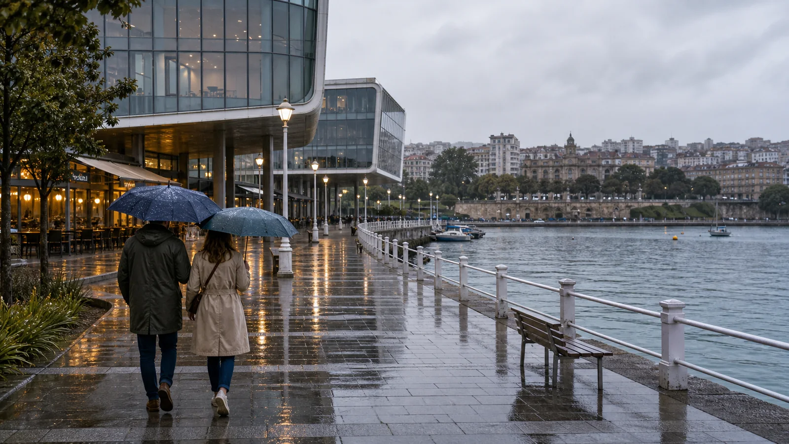 Pareja con paraguas paseando por Santander junto a la bahia en un dia de lluvia